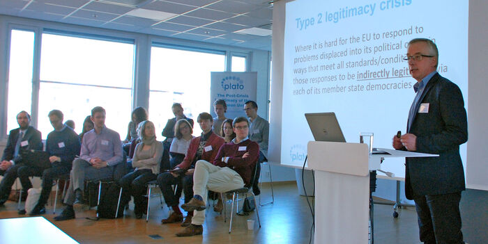 Chris Lord speaking next to the 15 PhD researchers